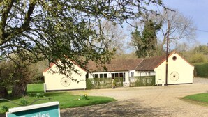 A sign for Bartles Lodge with a gravel driveway leading to a building with a tiled roof and a wheel feature on the side. - Bartles Lodge (Dereham)