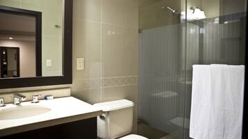 Een moderne badkamer met een douche met glazen wand, een wit toilet en een wastafel met spiegel erboven.