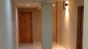 A hallway with tiled flooring, a wooden door at the end, and a pillar with a light fixture.