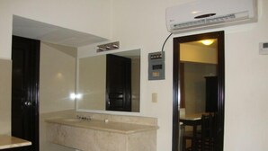 A bathroom with a large mirror, a sink, and an air conditioning unit mounted on the wall.