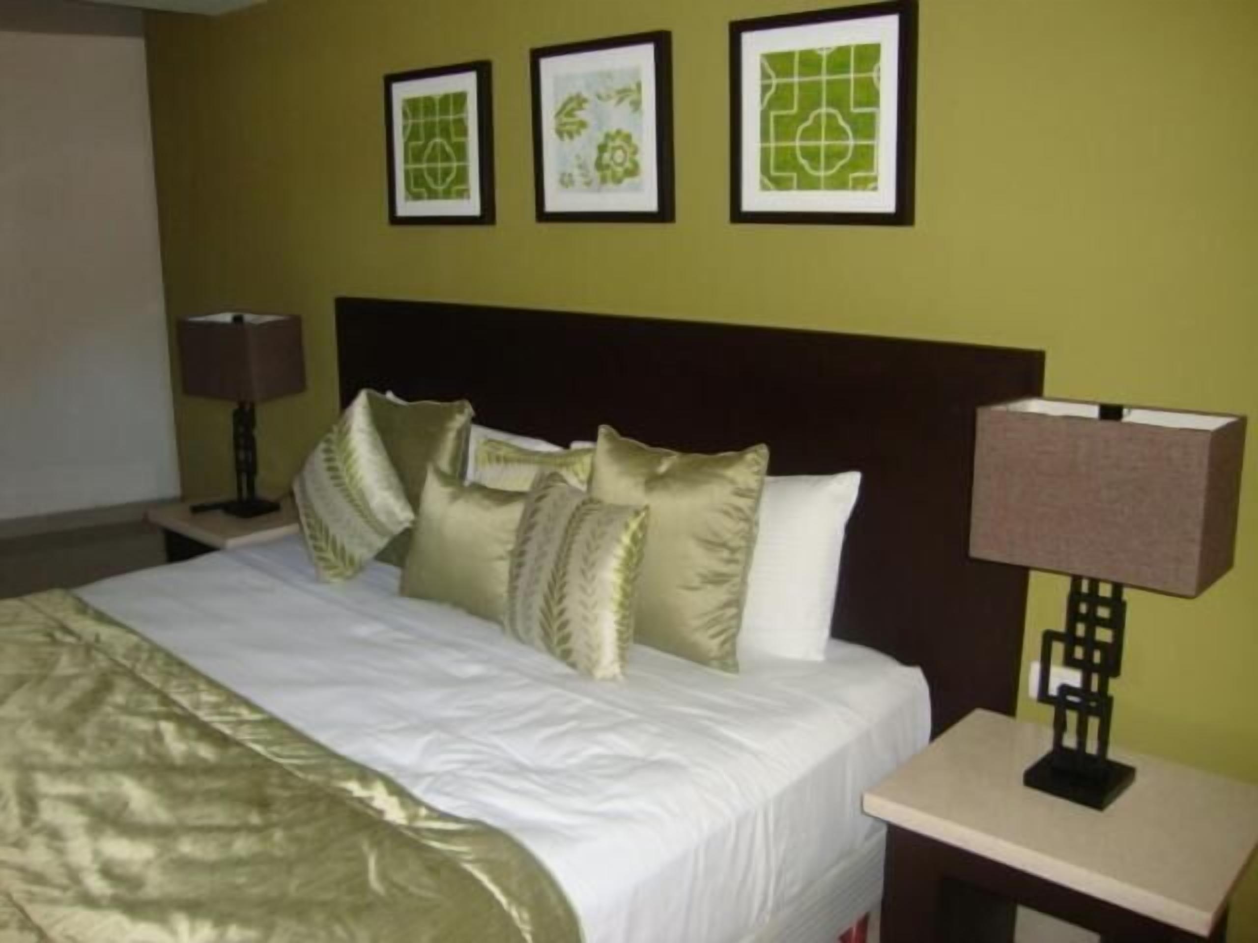 Ein Hotelzimmer mit einem Bett, einem Nachttisch und drei gerahmten Bildern an der Wand.
