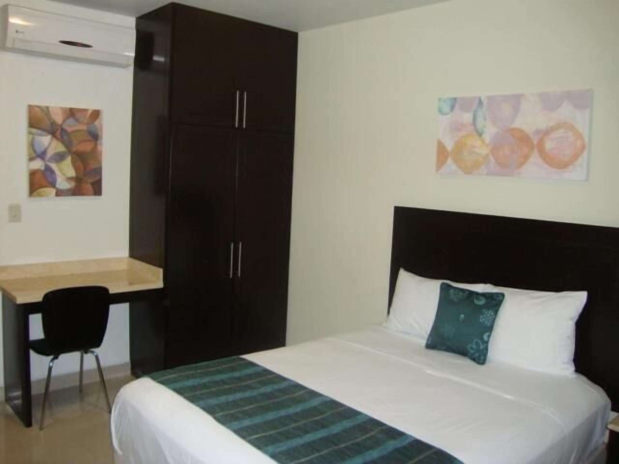 Une chambre d’hôtel avec un lit, un bureau et une armoire.