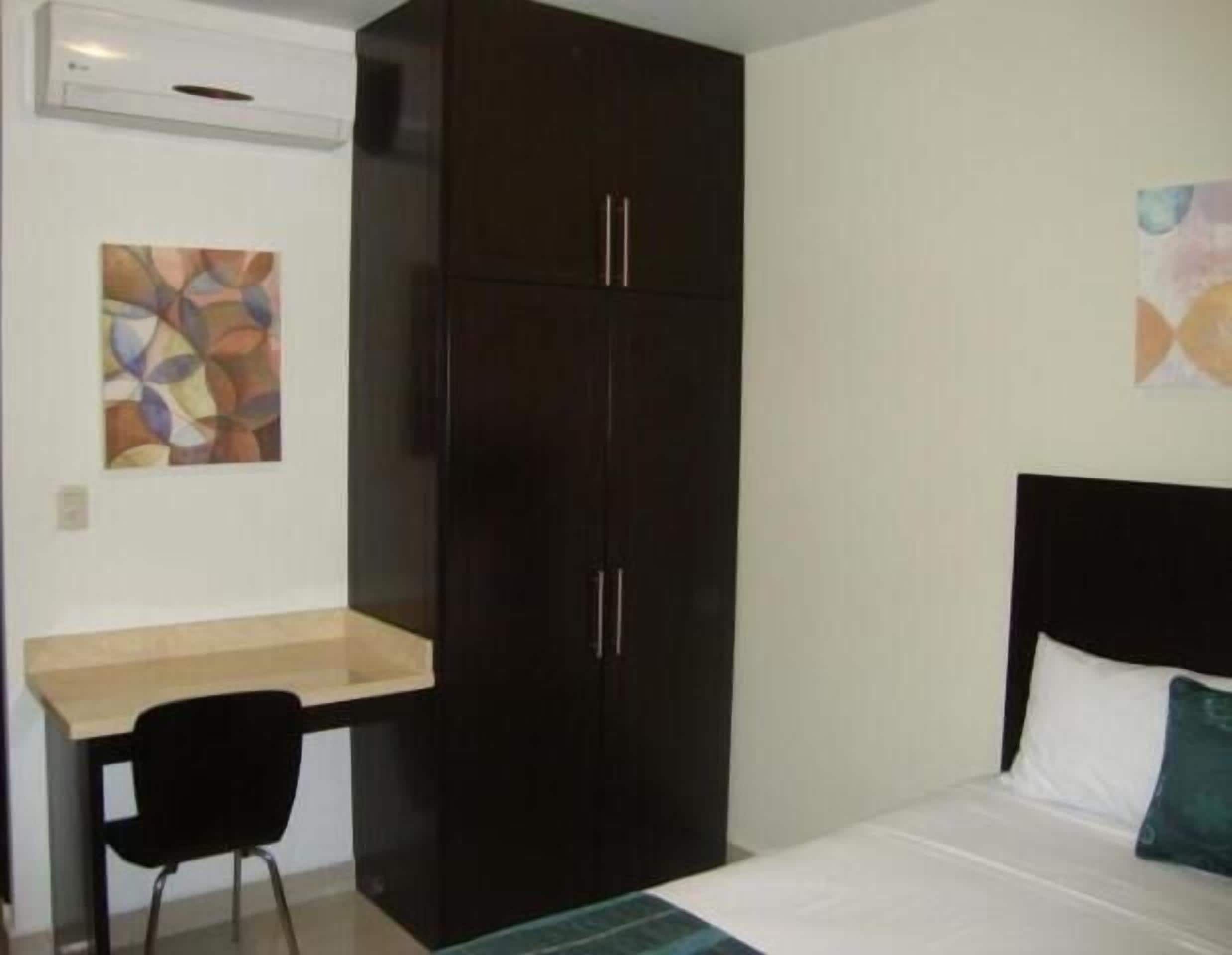 Een slaapkamer met een bed, bureau en garderobe.