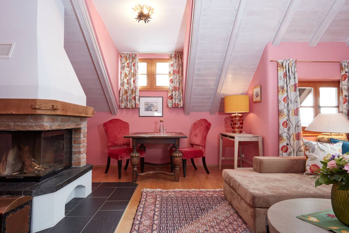 Una habitación acogedora con chimenea, una mesa de comedor con sillas, un sofá y una mesita auxiliar con lámpara.