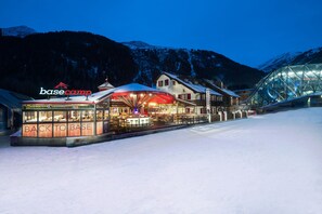 A basecamp building with a 'Back to Base' sign, surrounded by snow-covered mountains and a glass structure. - Schlosshotel Bergschlössl (Sankt Anton am Arlberg)
