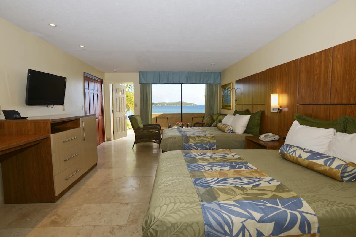 Ein Hotelzimmer mit Bett, Schreibtisch, Fernseher und Meerblick.