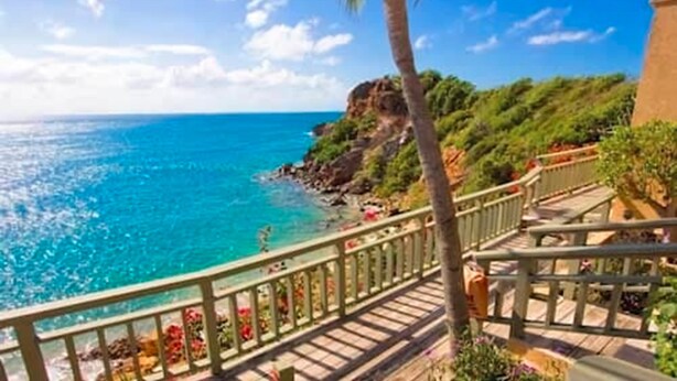 A coastal view with a clear sky, a staircase leading down to a beach, and a palm tree. - Lindbergh Bay Hotel and Villas (St. Thomas)