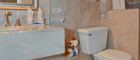 Un bagno con un lavabo in marmo, un WC e uno scaffale in vetro sopra il water.