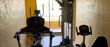 Une salle de sport équipée d’un tapis de course, d’un vélo elliptique et d’un vélo d’appartement.