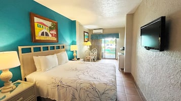 Une chambre d’hôtel équipée d’un lit, d’une télévision, d’un bureau avec une chaise et d’une fenêtre donnant sur l’extérieur.