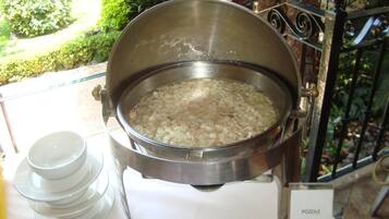 A large pot of soup on a table with a sign labeled "POZOLE".