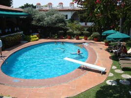 Una piscina al aire libre, sillones reclinables de piscina