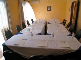 Un salón de conferencias con mesas largas, sillas, botellas de agua y tarjetas de identificación.