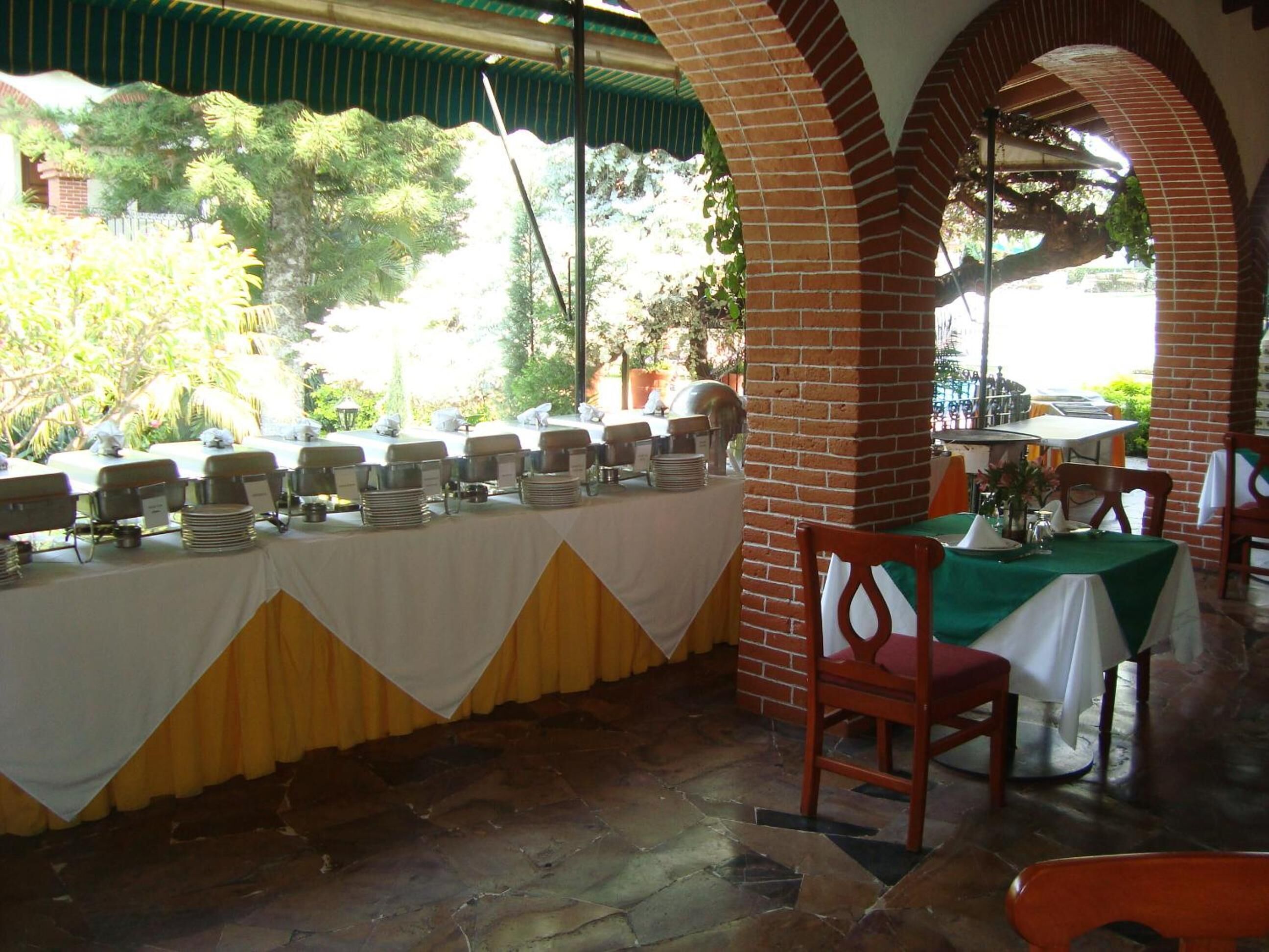 A restaurant with outdoor seating, brick arches, and a buffet setup.