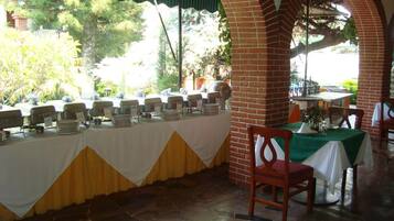 A restaurant with outdoor seating, brick arches, and a buffet setup.