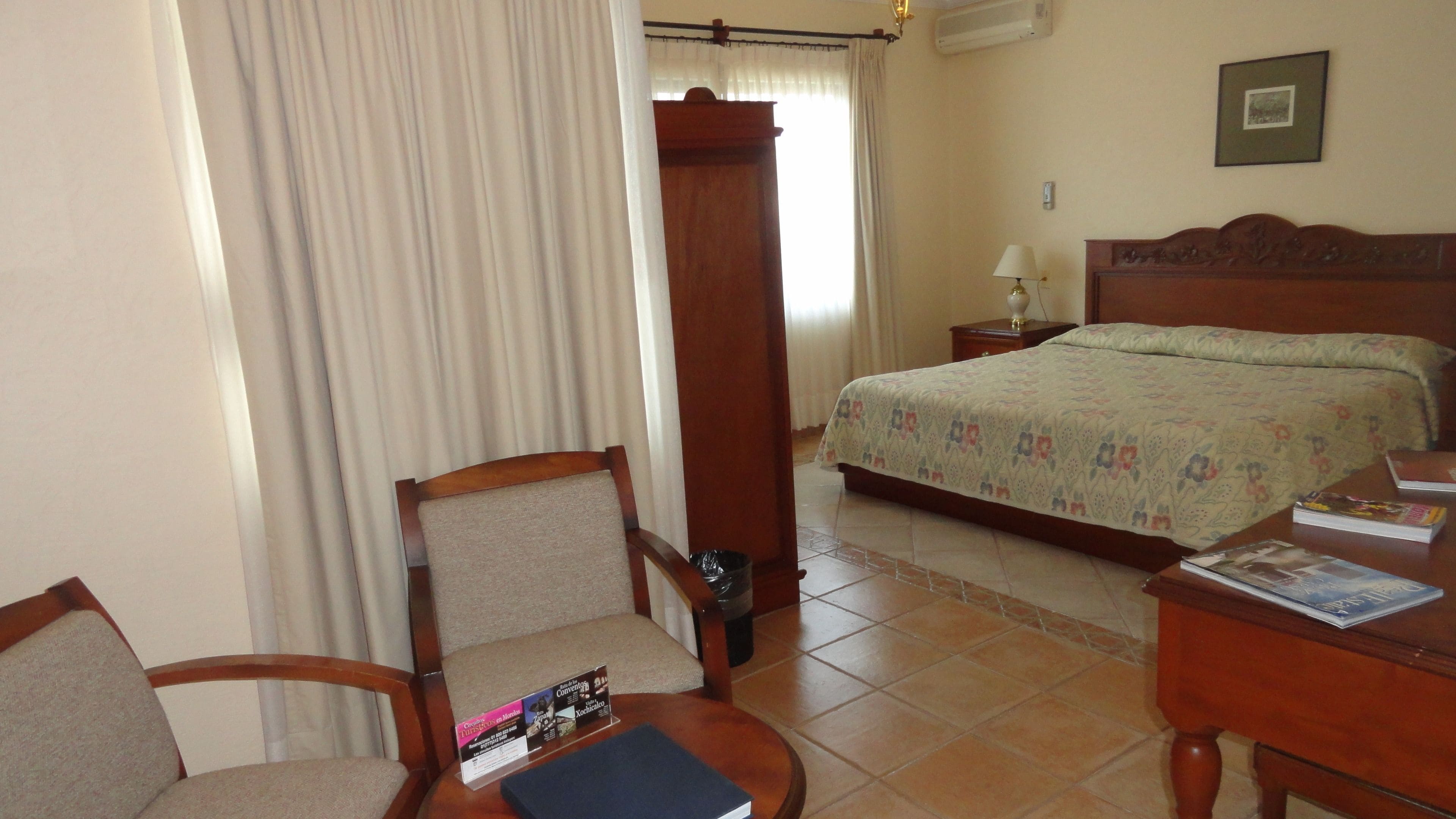 Une chambre d’hôtel avec un lit, une chaise, une petite table et une table de chevet.