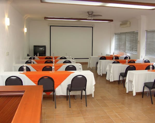 A conference room with multiple tables and chairs, a projector screen, and a ceiling fan. - Hotel Vista Hermosa (Cuernavaca)