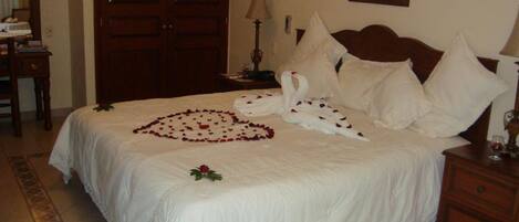 A neatly made bed with a heart-shaped arrangement of rose petals and a swan design on the bedspread.