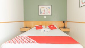 A hotel room with a bed, two nightstands, a framed picture on the wall, and a red and white bedspread. - Mangabeiras Hotel (Goiania)