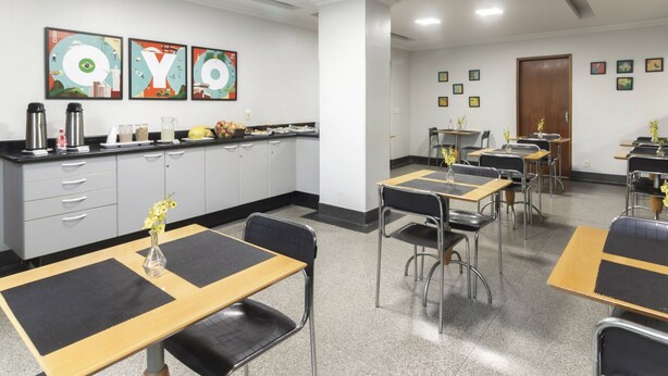 A hotel dining area with tables, chairs, and a kitchen counter. - Mangabeiras Hotel (Goiania)