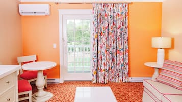 Una habitación con una mesa blanca, dos sillas, un sofá, una lámpara y una ventana con cortina.