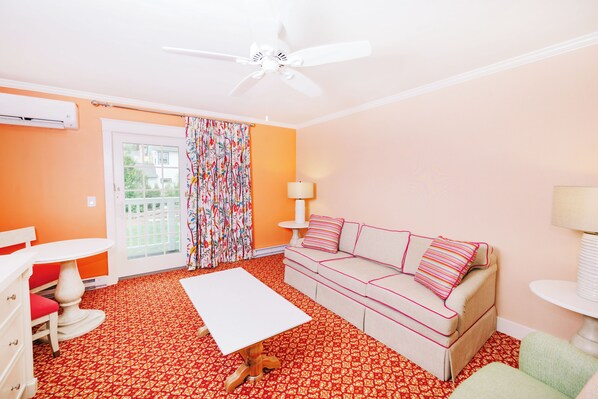 Una habitación con ventilador de techo, un sofá, una mesa y una alfombra estampada.