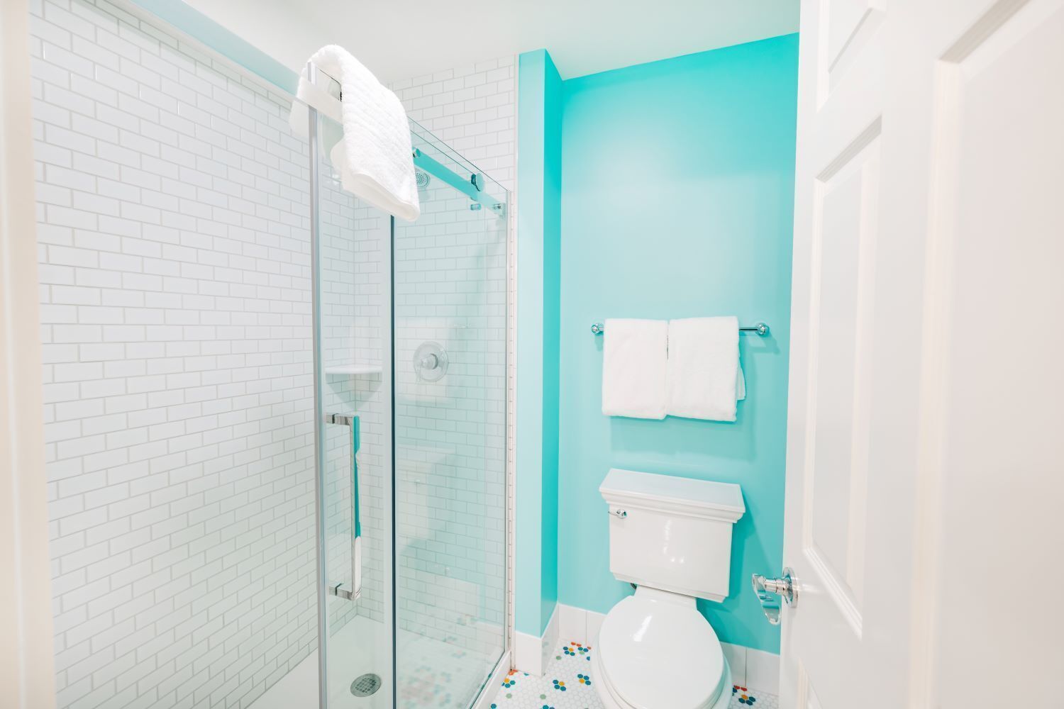 A bathroom with a glass shower enclosure, a toilet, and a sink.