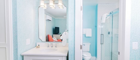 A bathroom with a white vanity, a large mirror, and a shower area with a glass door.