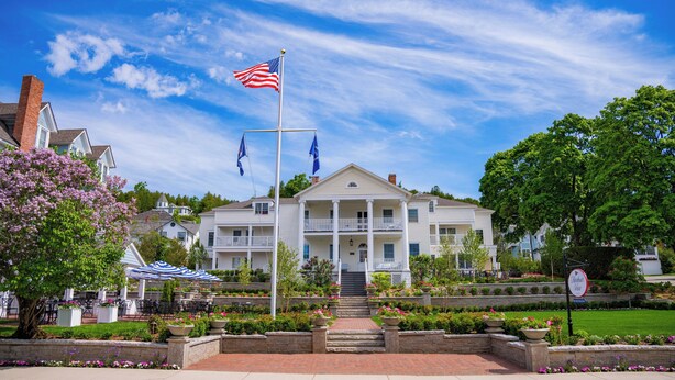 A two-story building with a front porch, a flagpole with an American flag, and a sign indicating 'Harbor View.'
