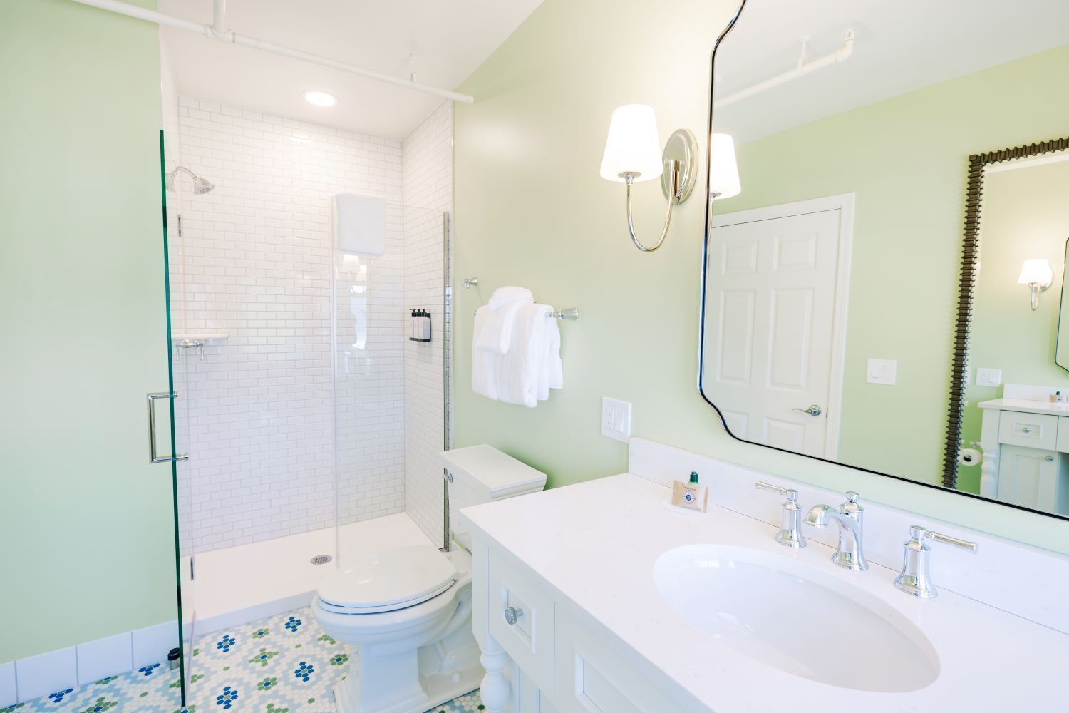 Un baño con cabina de ducha de vidrio, inodoro blanco y un espejo grande.