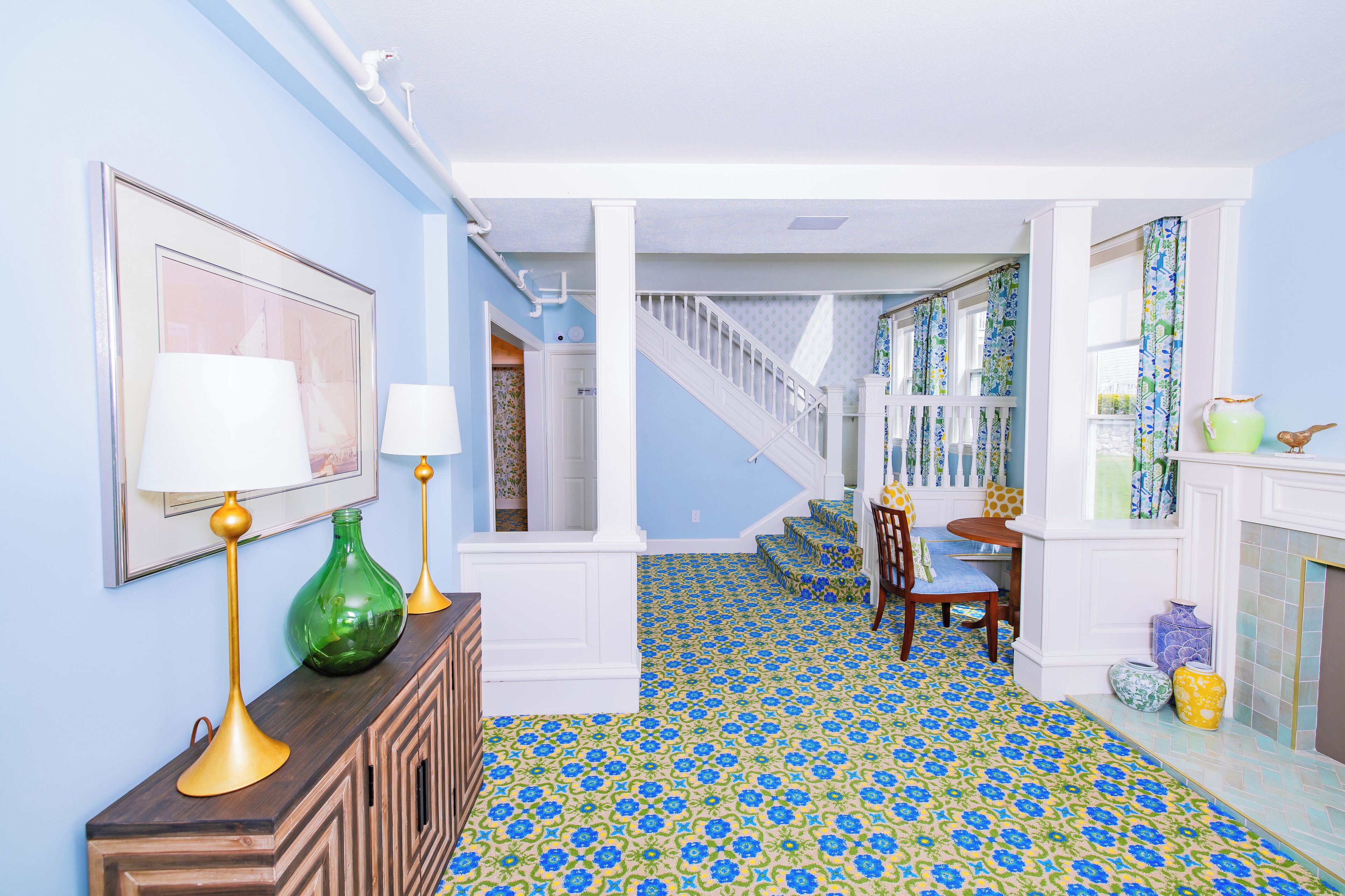 A hallway with patterned flooring, a staircase, and a dining area with chairs and a table.