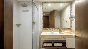 A modern bathroom with a glass-enclosed shower, a sink with a mirror above it, and a wooden vanity with a towel rack.