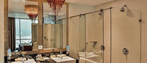 Une salle de bain moderne avec deux vasques, un grand miroir, un lustre et une douche à l’italienne.