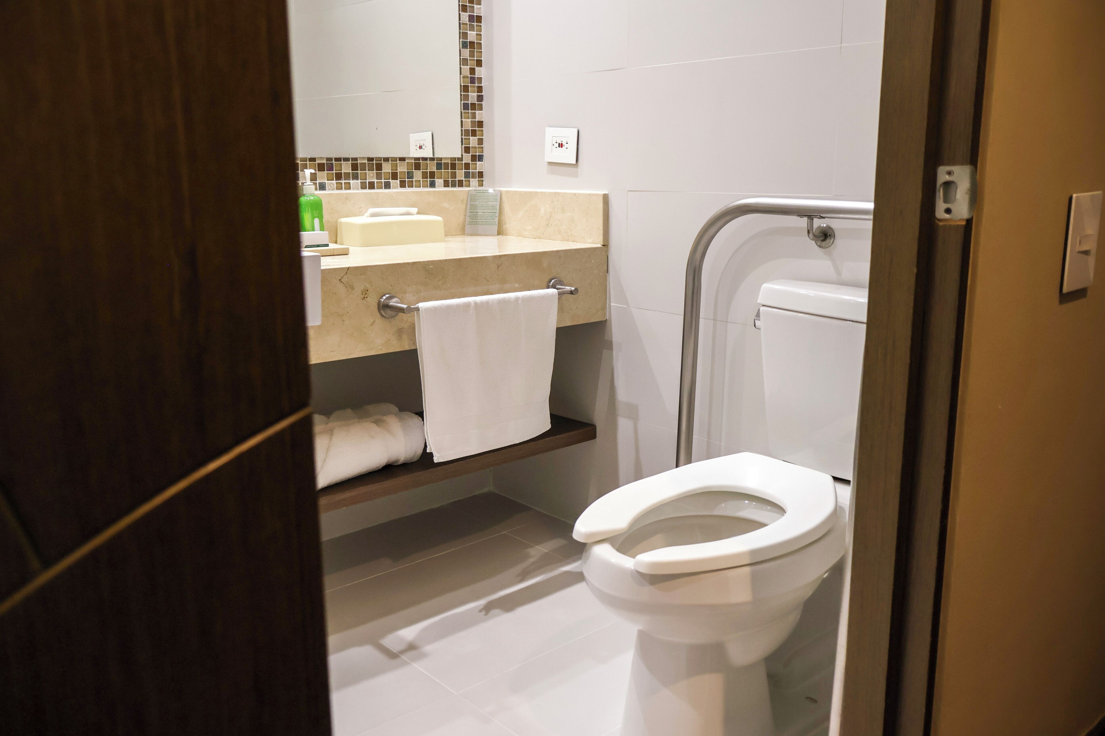 Casa de banho moderna com sanita branca, lavatório com espelho e um porta-toalhas.