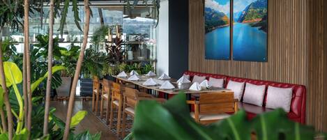 A restaurant with wooden tables, red cushioned seating, and large windows overlooking a mountainous landscape.