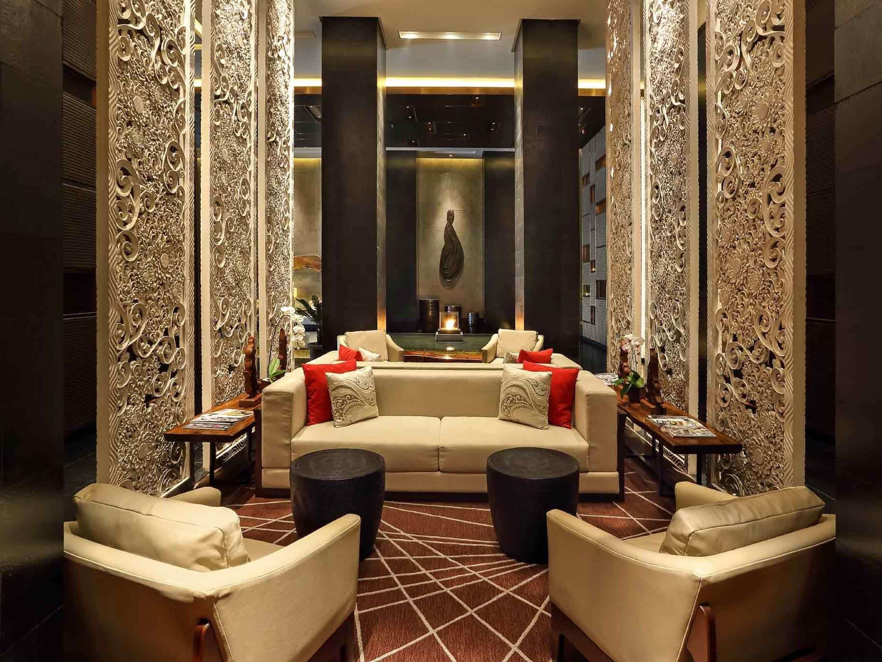 Una sala de estar moderna con un sofá, dos sillones, una mesita de centro y paneles decorativos.