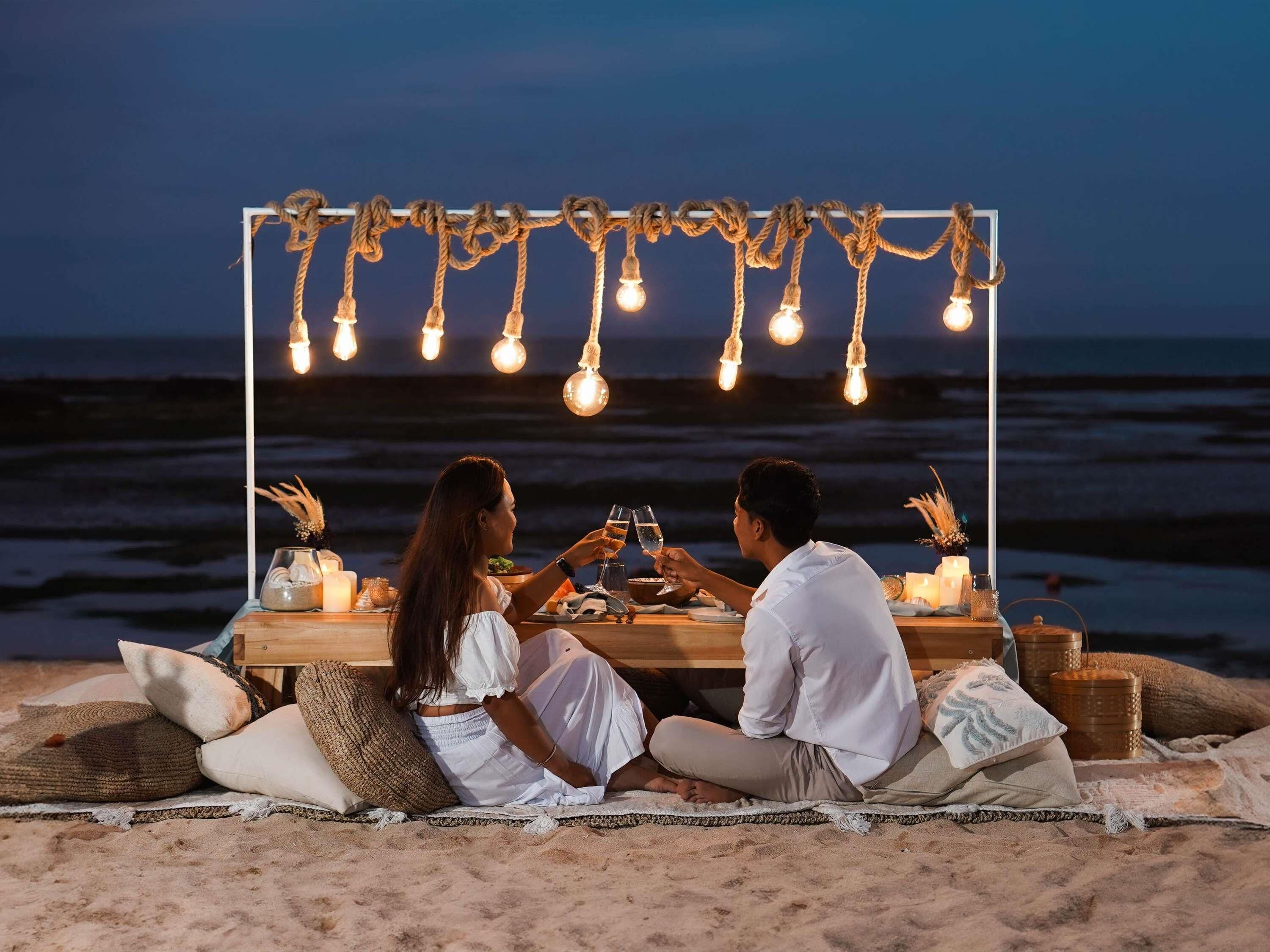 A beachside dining setup with a table, chairs, and a view of the ocean.