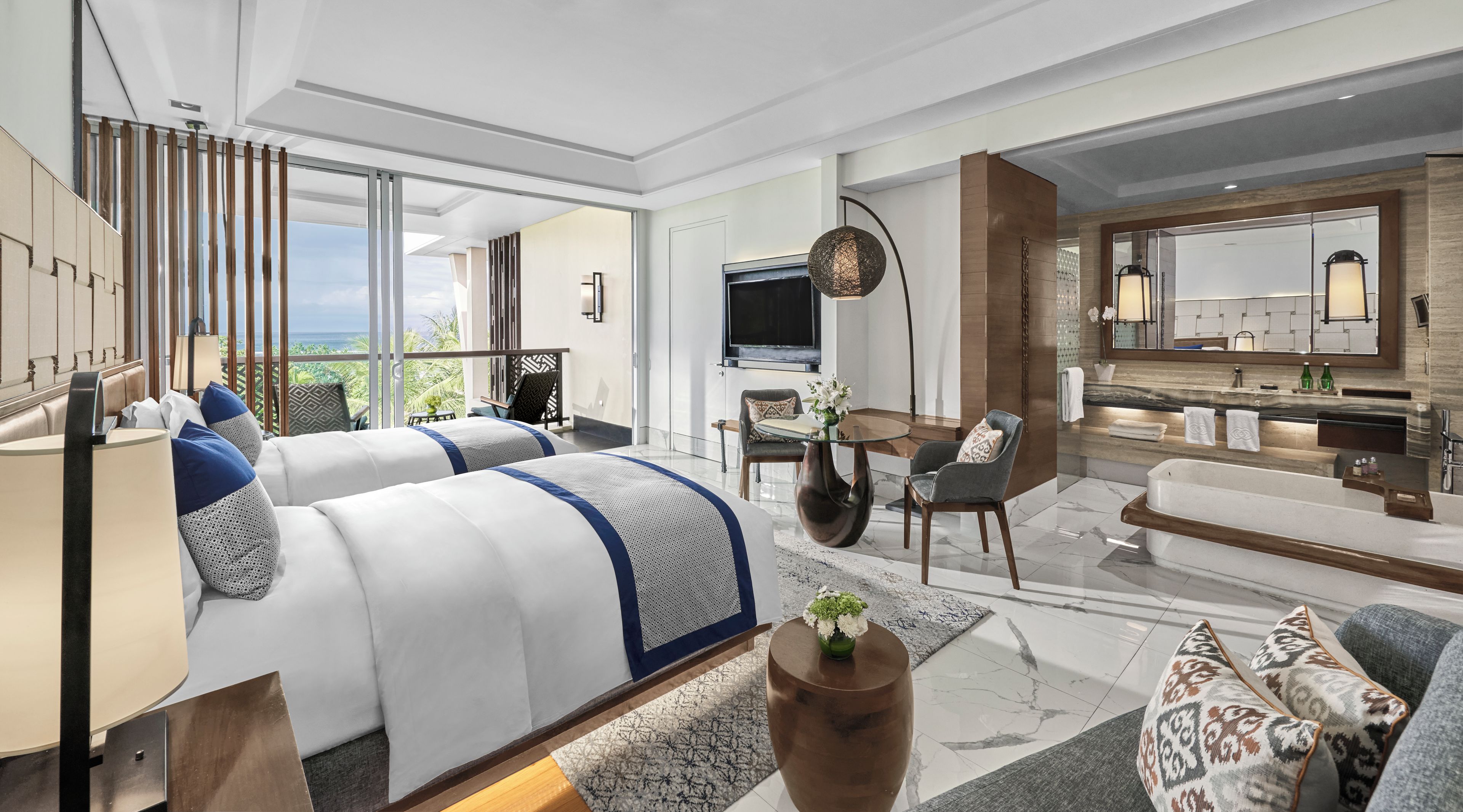A modern hotel room with a balcony, a TV, a dining area, and a bathroom with a large mirror.