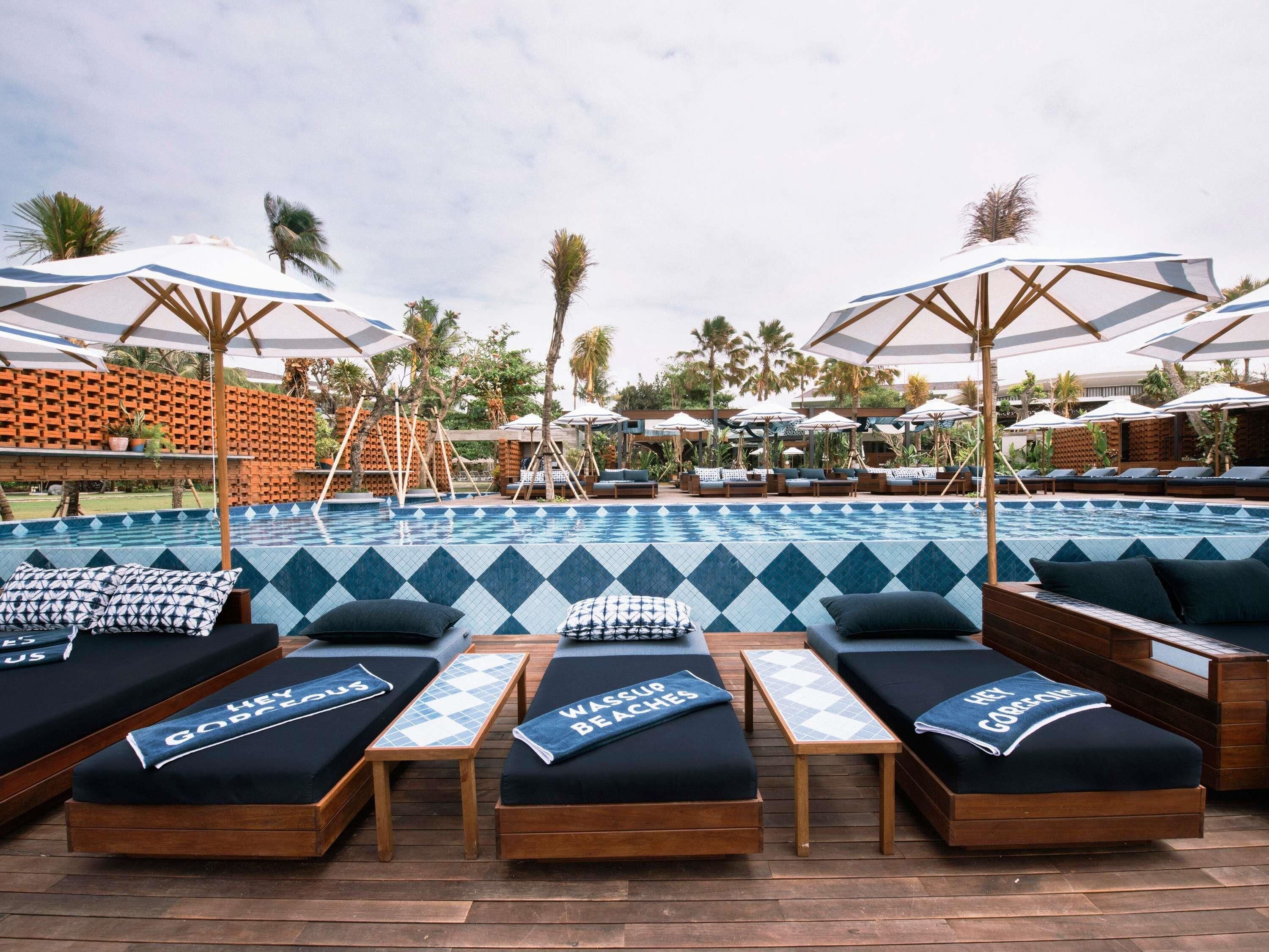 A poolside area with lounge chairs, umbrellas, and a tiled pool.
