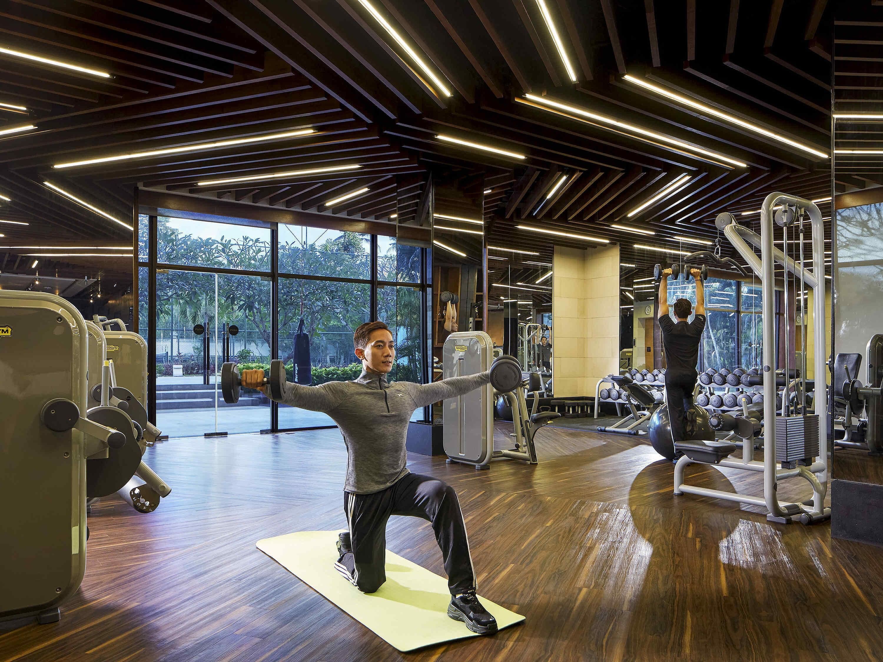 Une salle de sport équipée de matériel d’exercice, dotée de grandes fenêtres et d’un plancher en bois.