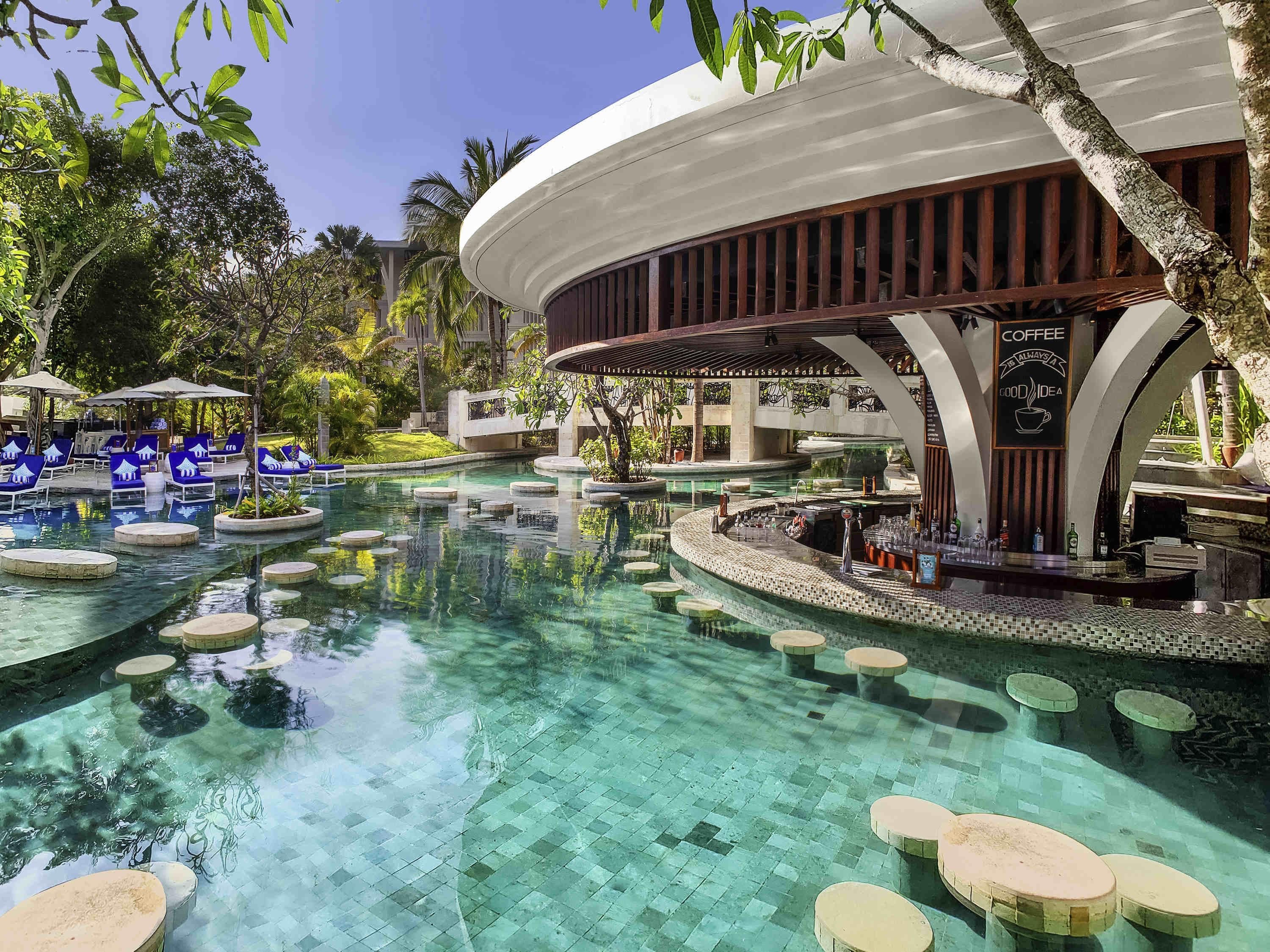 A pool area with lounge chairs, a bar, and a covered seating area.