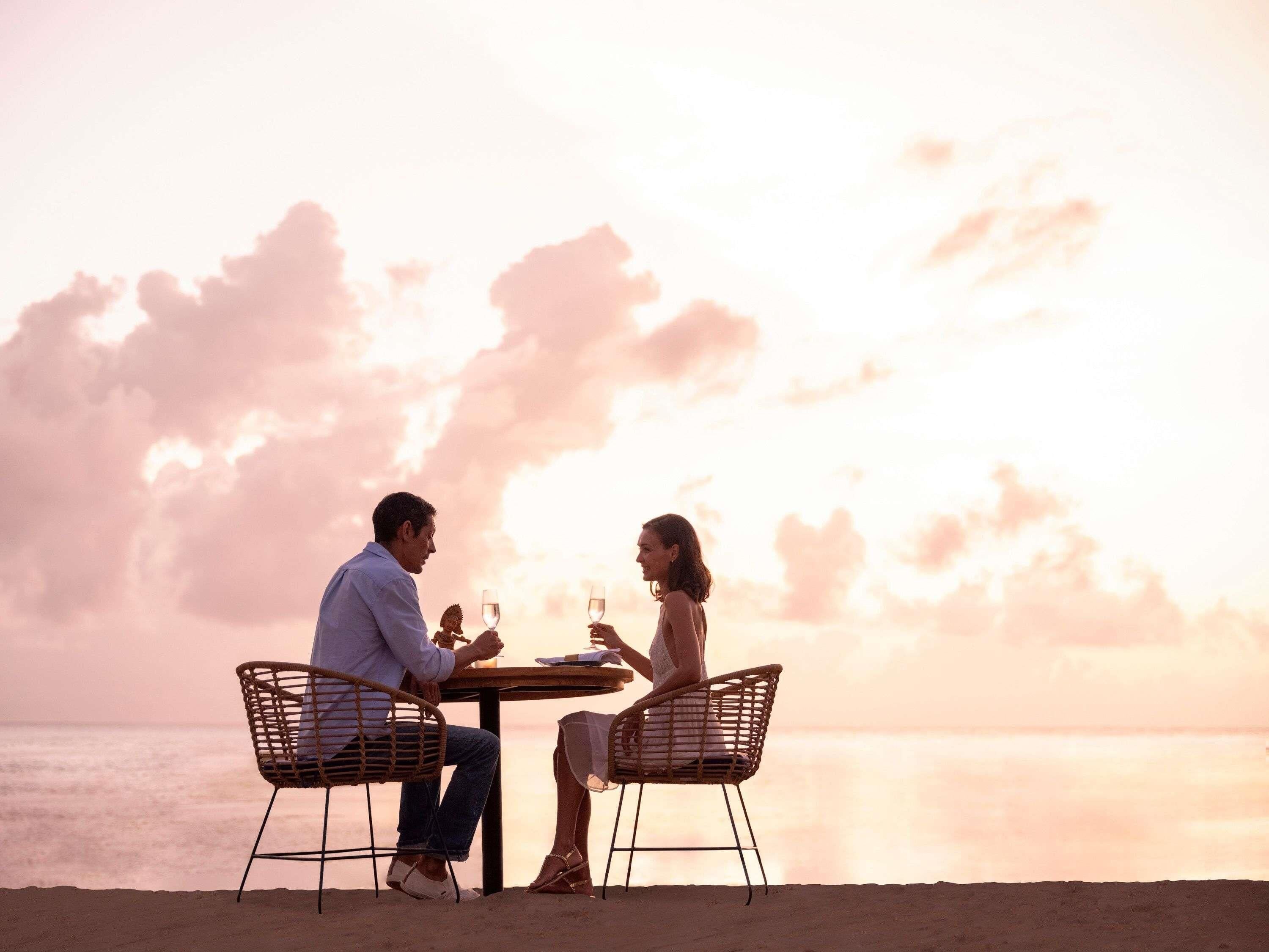 Ein Paar speist an einem Tisch mit Blick auf das Meer und den Himmel.
