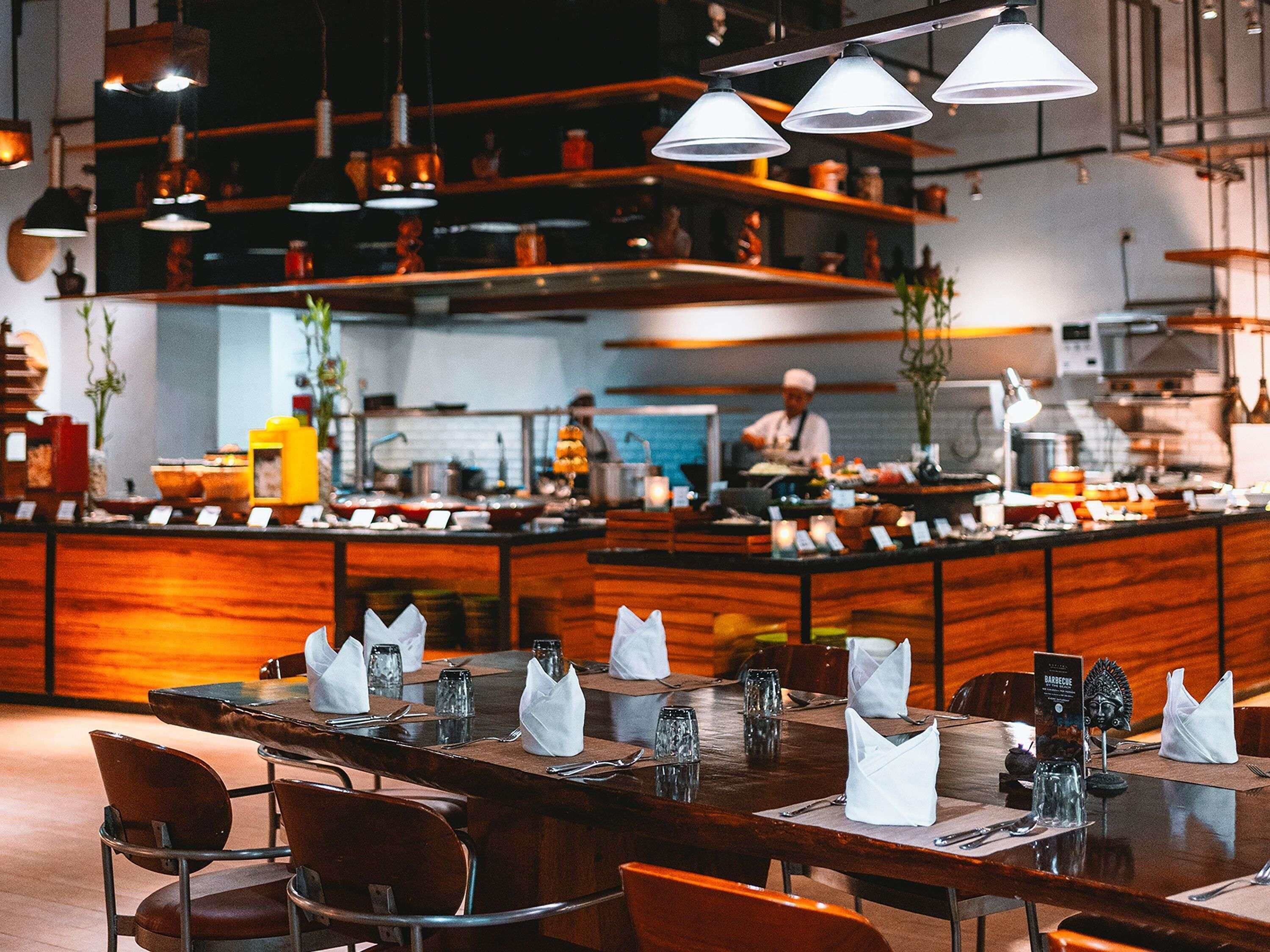 Een restaurantinterieur met houten tafels, witte servetten en hangende吊り下げ灯