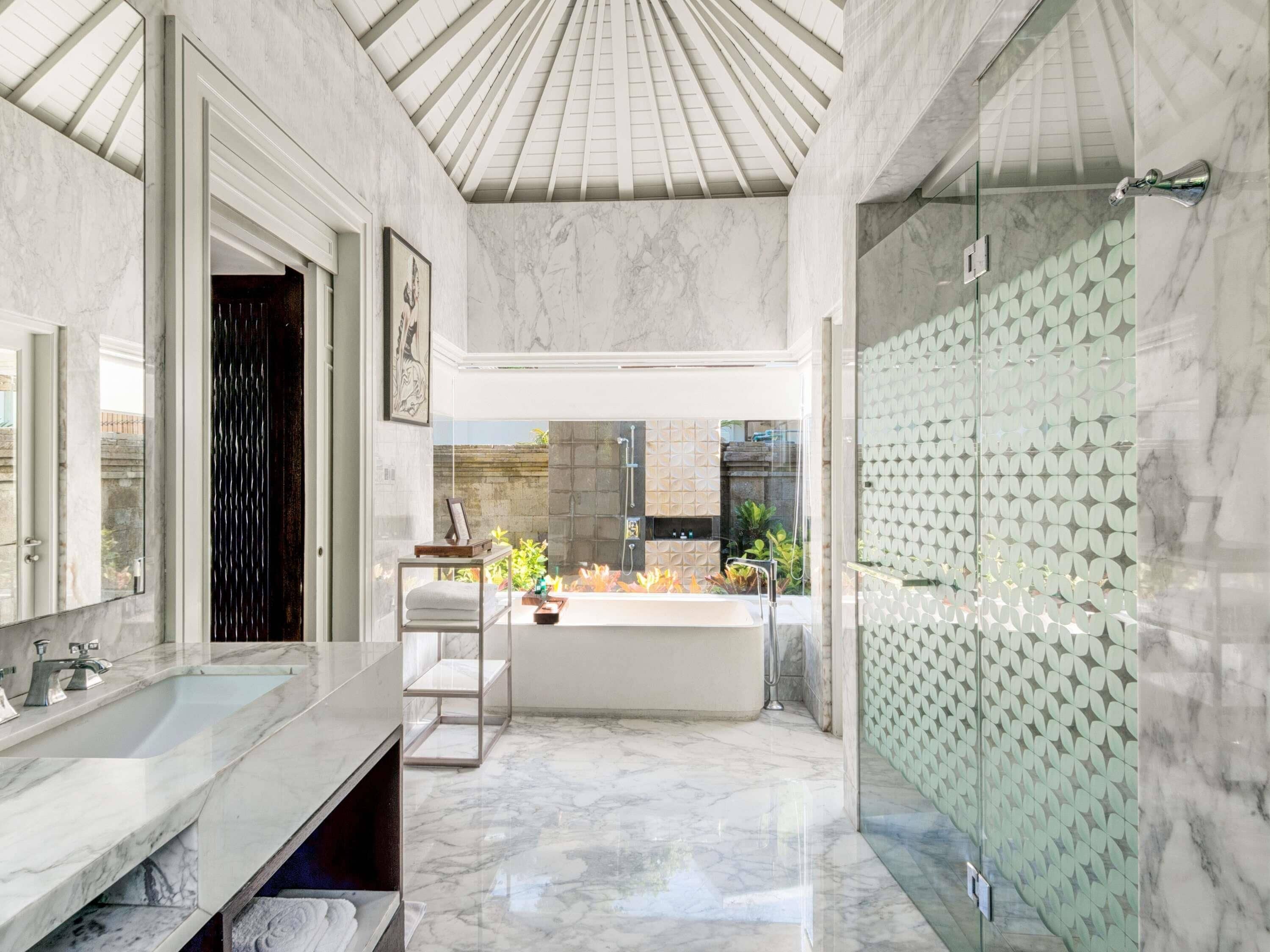 A modern bathroom with a large mirror, a bathtub, and a shower area.