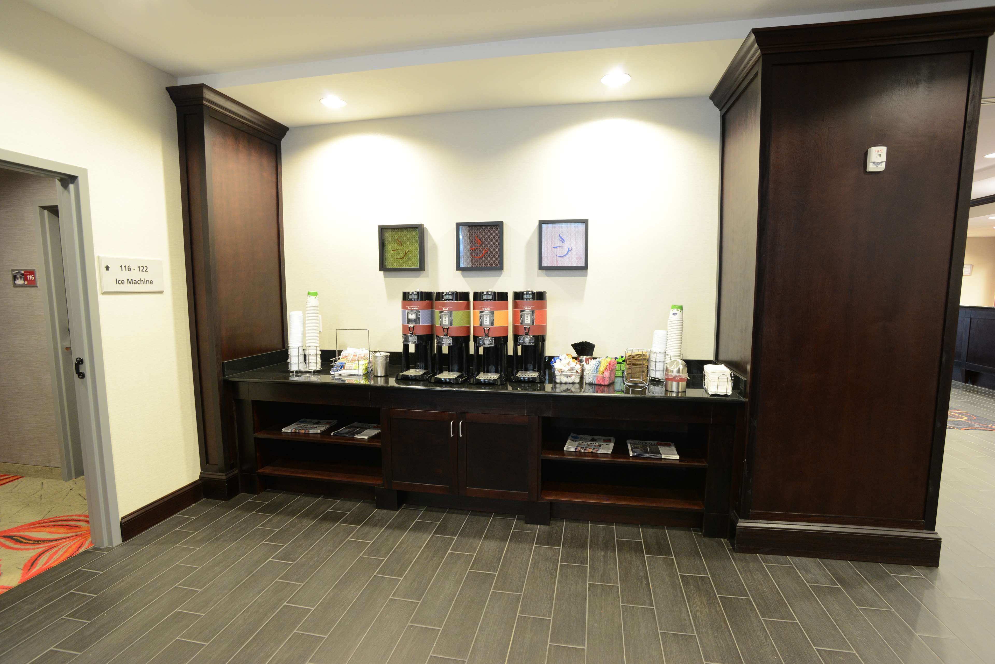 A hotel reception area with a coffee station, a sign indicating the location of the ice machine, and a door to the left.