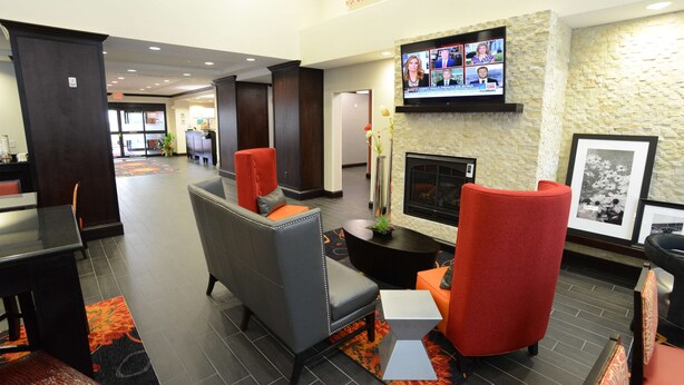 Un hall con asientos, chimenea y un televisor que muestra varios canales de noticias.