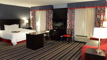 Una habitación de hotel con cama, escritorio, silla y televisor.