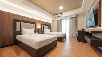 A hotel room with two beds, a TV, and a desk.