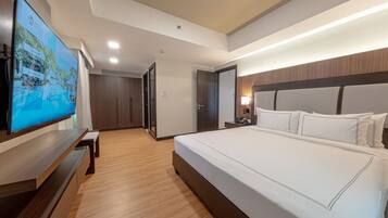 Een moderne hotelkamer met een groot bed, een flatscreen-televisie, houten vloeren en een houten hoofdeinde.