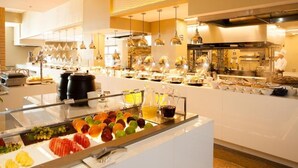 A buffet area with a variety of fruits and beverages, a kitchen in the background, and a modern interior design. - Widus Hotel Clark (Mabalacat City)